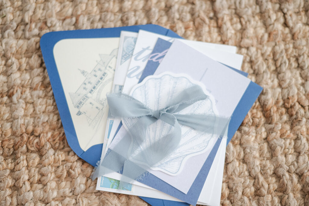 Full custom coastal wedding stationery suite with venue illustrations, shell RSVP and blue envelopes